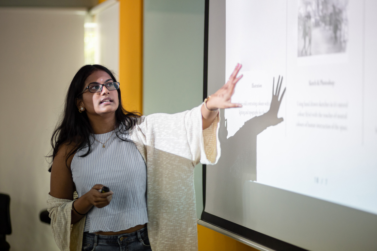 Asian college student is making a presentation in front of projector screen