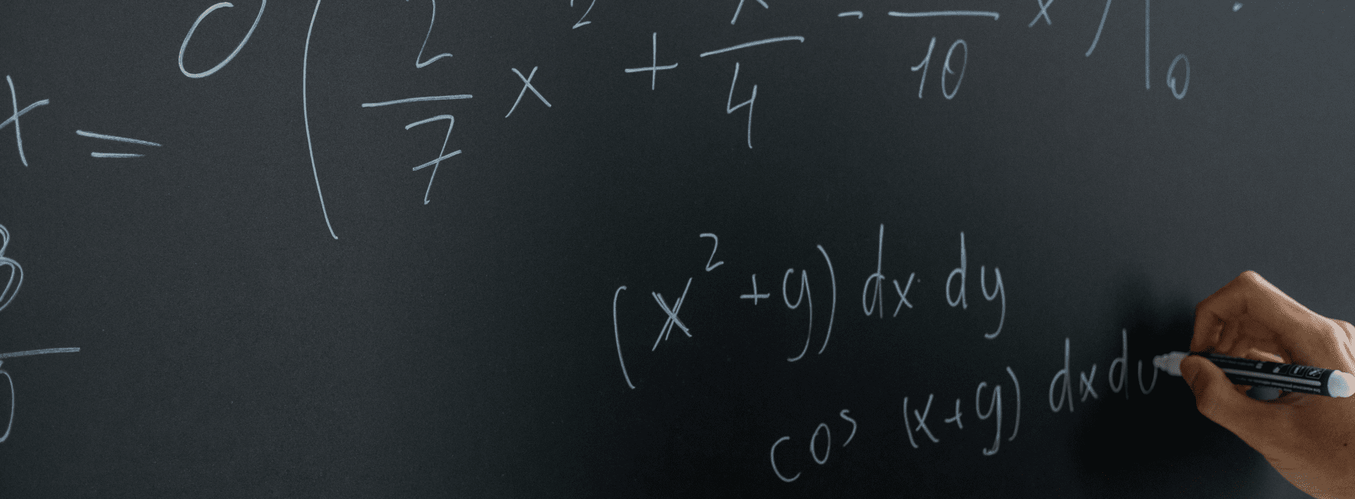 Hand writing mathematical equations on a blackboard with a white marker.