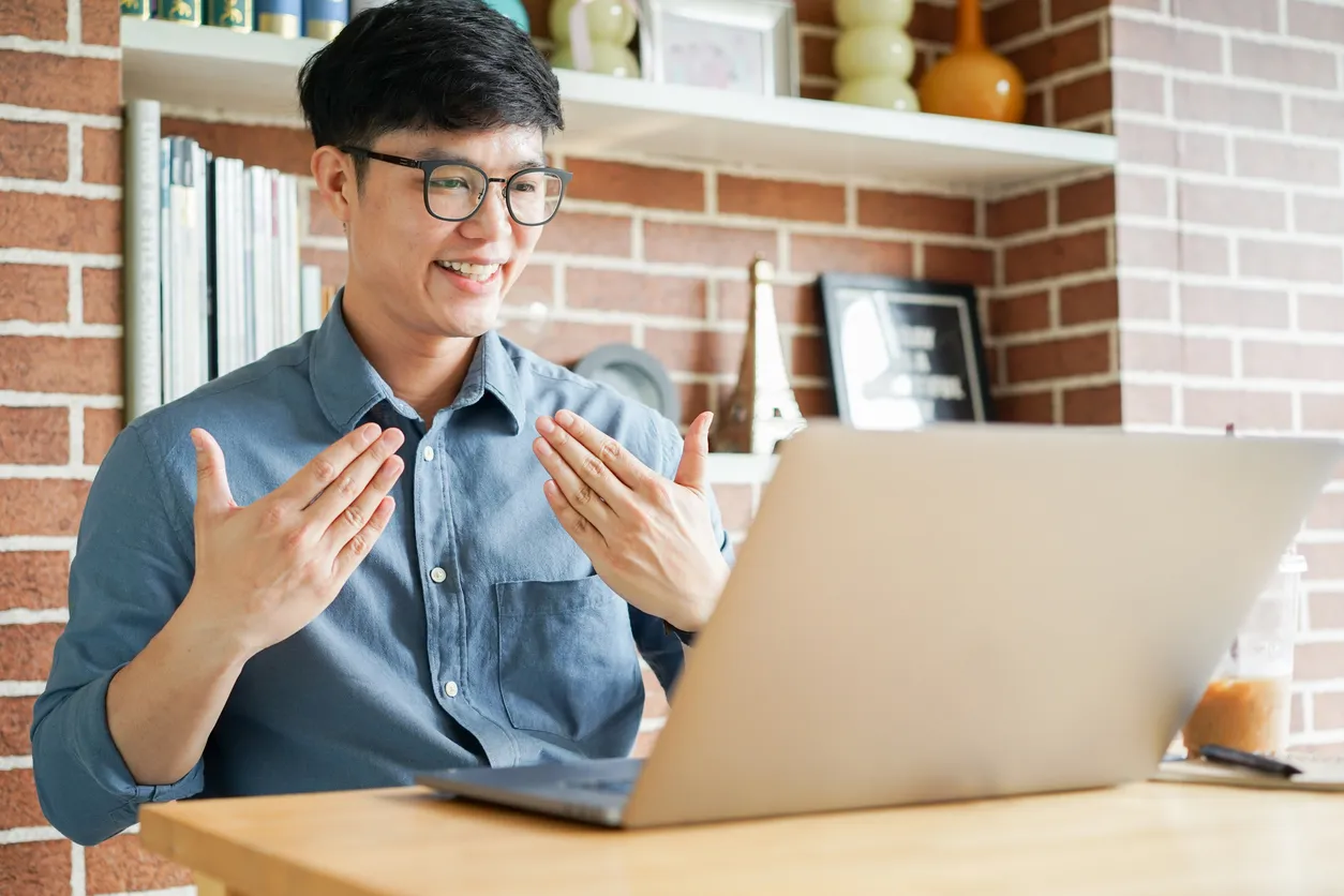 Close up asian man make gesture hand about happy sign language to teaching or learning from webinar in home for lifestyle concept