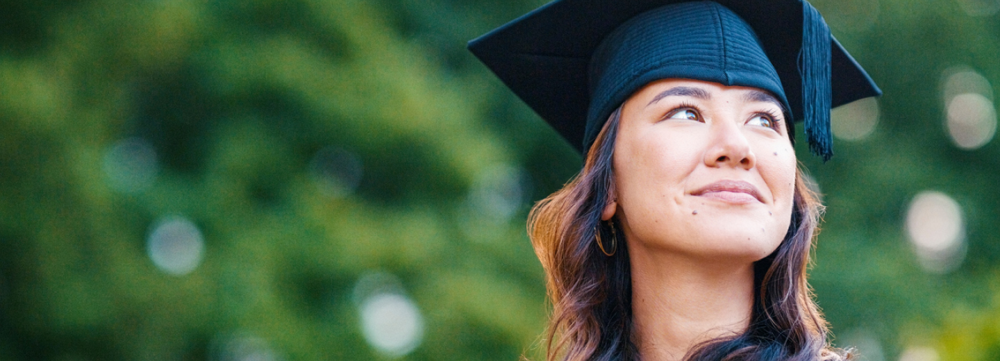 A woman wearing a graduation gown and cap, smiling proudly as she celebrates her academic achievement.