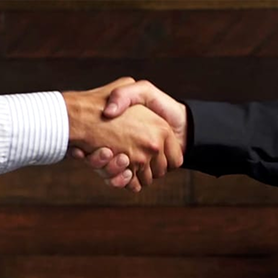 Two people shaking hands in front of a wooden background.